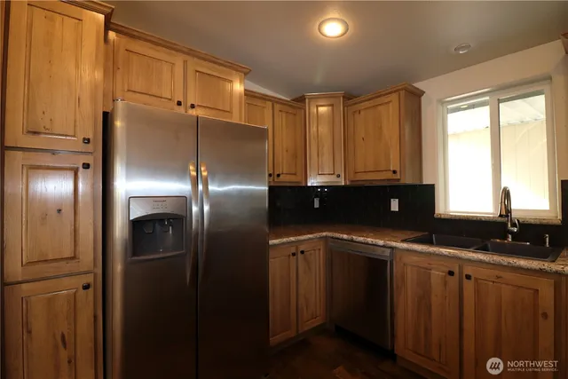 a kitchen with granite countertop stainless steel appliances a refrigerator sink and cabinets