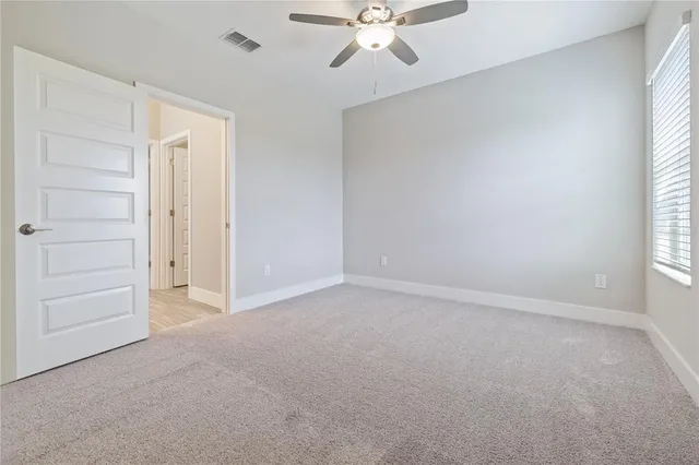 an empty room with a window and a ceiling fan