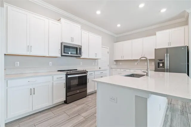 a kitchen with stainless steel appliances granite countertop a stove a sink and a refrigerator with white cabinets