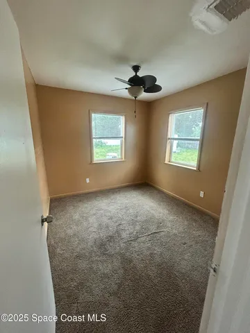 an empty room with windows and ceiling fan