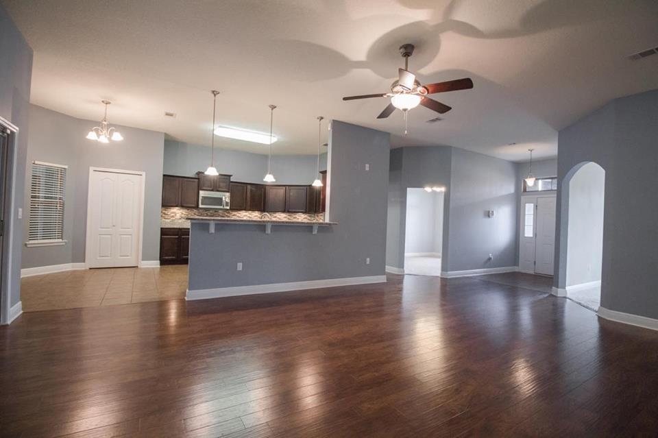 4500 Hermosa Road Crestview, FL 32539 - Photo 7 of 27 an empty room with wooden floor a ceiling fan and kitchen view