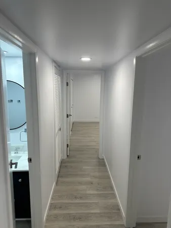 a view of a hallway with wooden floor and a bathroom