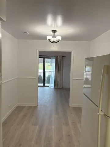 a view of a hallway with wooden floor and a bathroom