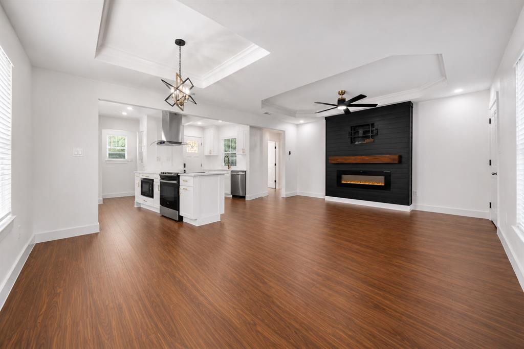 2831 Fordham Road Dallas, TX 75216 - Photo 5 of 8 Open-concept living space featuring wood-finish flooring, a contemporary ceiling fan, and a kitchen with stainless steel appliances and a center island