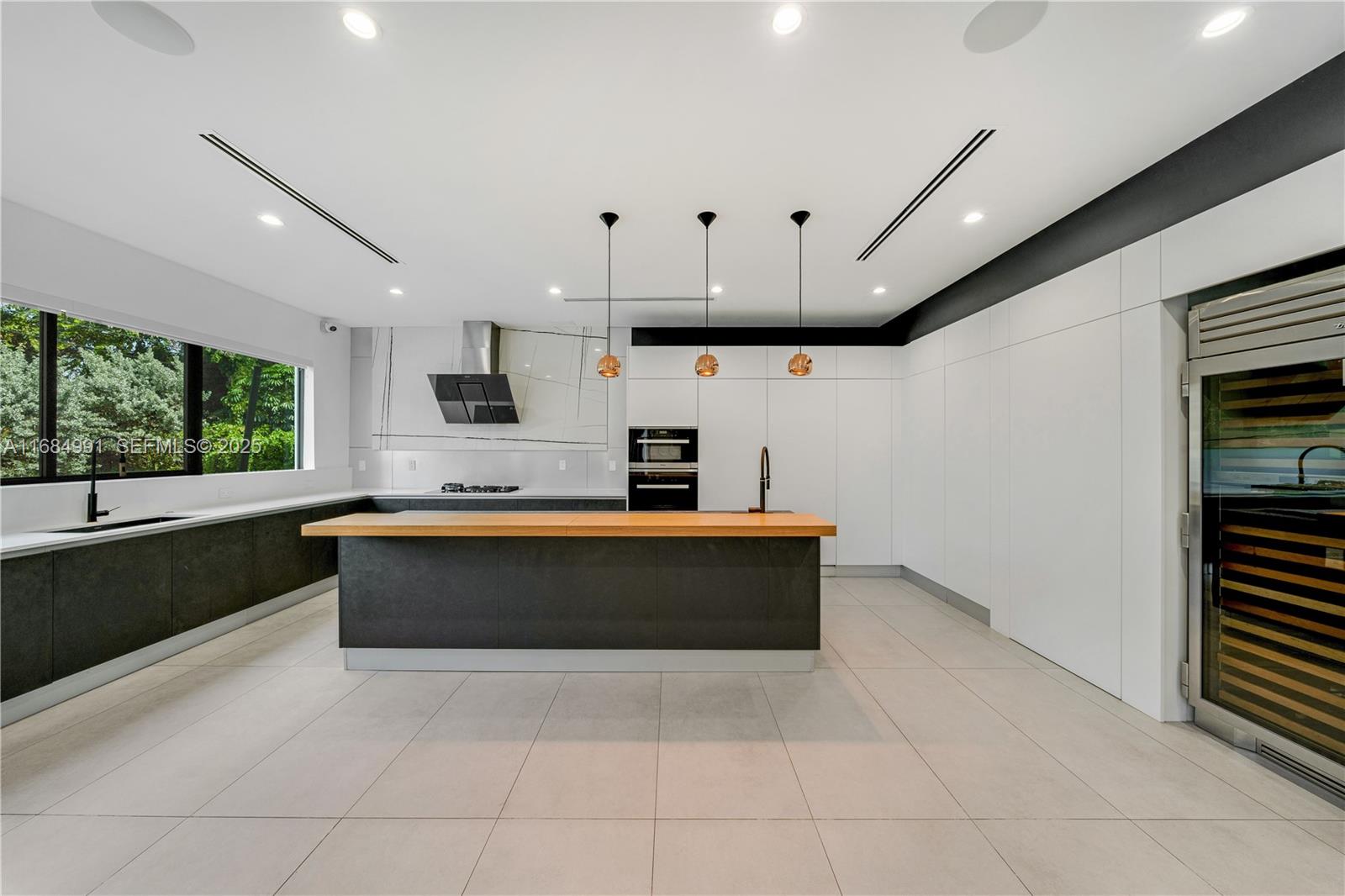 6695 Southwest 112th Street Pinecrest, FL 33156 - Photo 35 of 99 a large kitchen with stainless steel appliances a large counter top a stove a chimney a sink and a large window