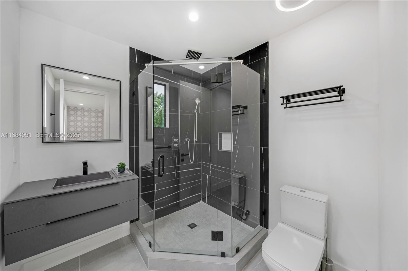 6695 Southwest 112th Street Pinecrest, FL 33156 - Photo 62 of 99 a bathroom with a shower sink mirror and toilet