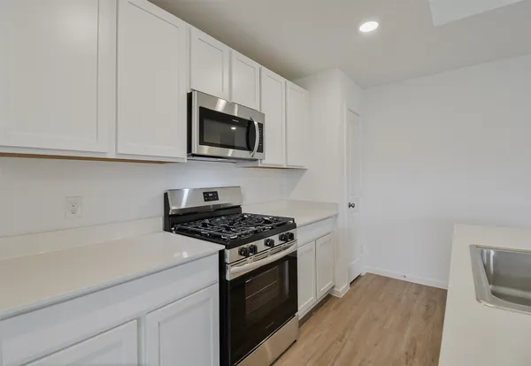 a kitchen with granite countertop a sink dishwasher a stove and a microwave oven with cabinets