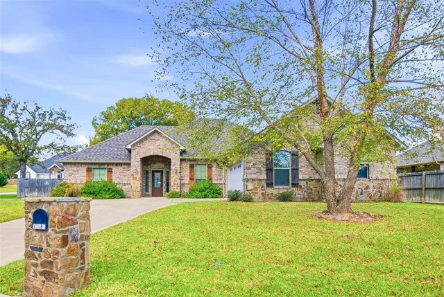 a front view of a house with a garden and trees