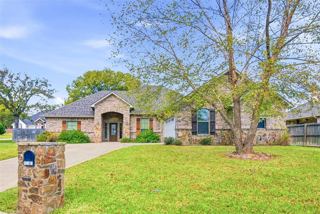 a front view of a house with a garden and trees