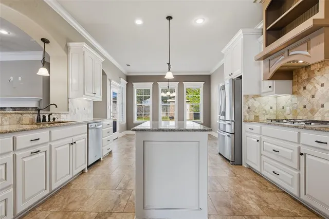 a large kitchen with granite countertop a large stove top oven and cabinets