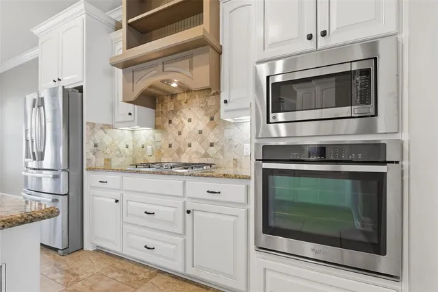 a kitchen with granite countertop white cabinets stainless steel appliances and a counter space