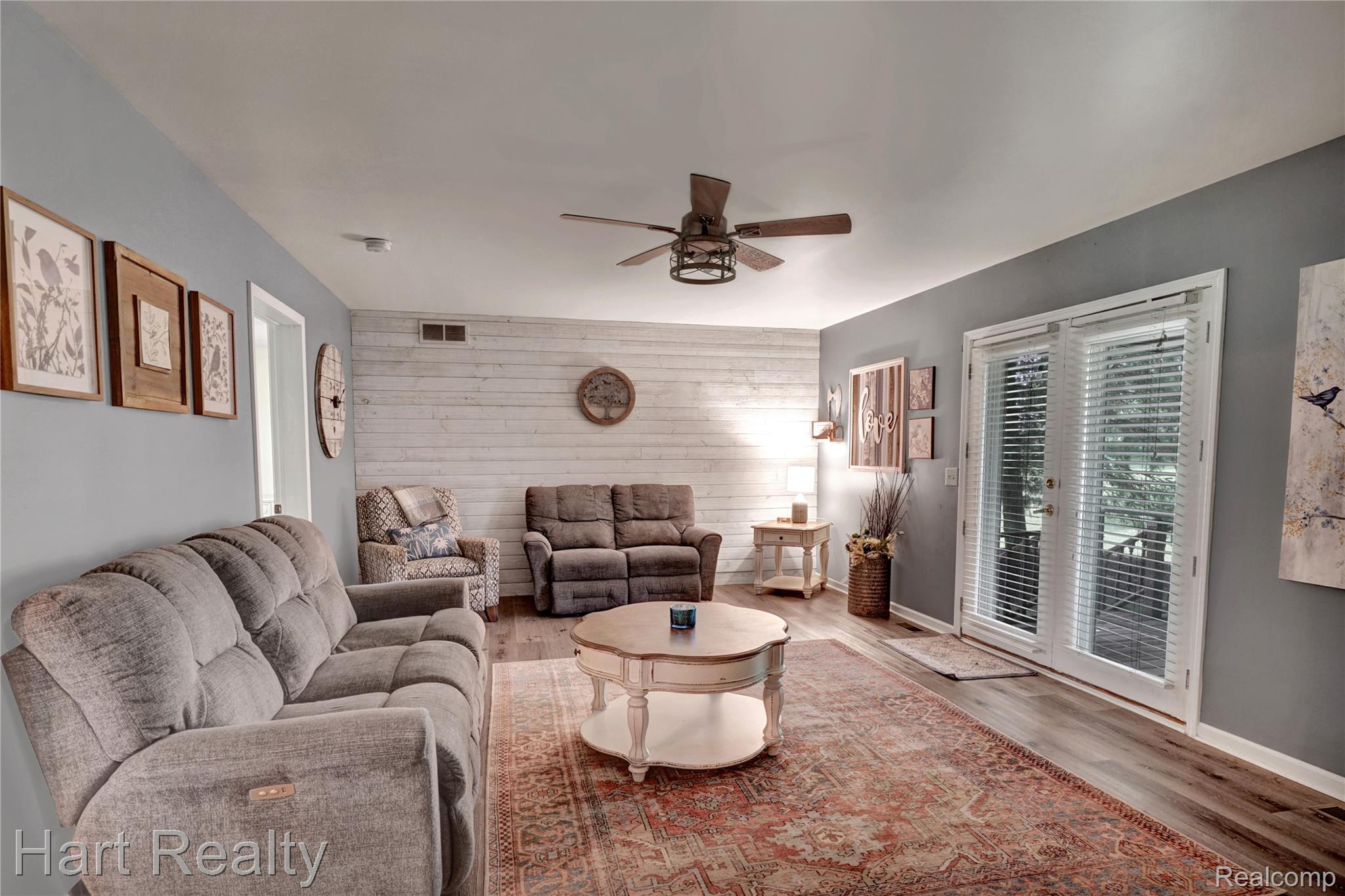 7167 Brown School Road North Branch, MI 48461 - Photo 14 of 51 Living area featuring light wood-finish flooring, a white shiplap accent wall, and a ceiling fan with integrated lighting