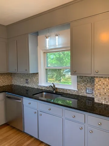a kitchen with granite countertop white cabinets and a sink