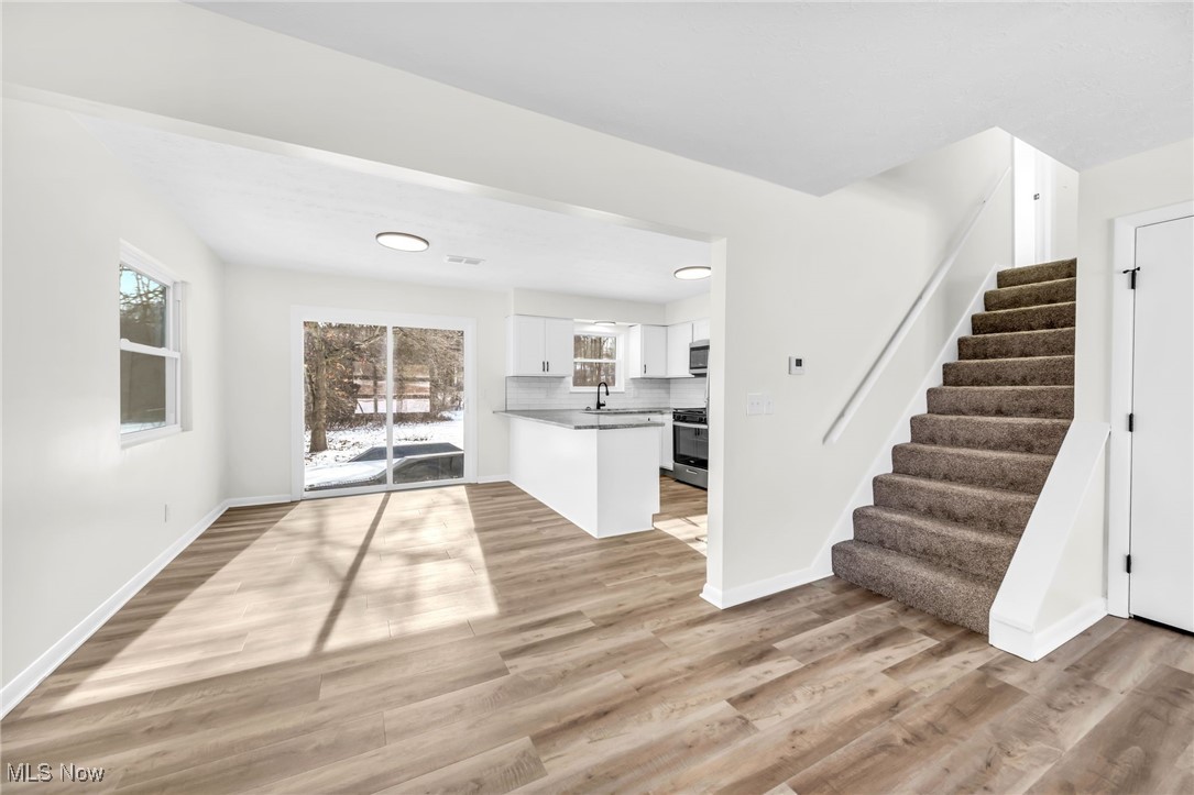 Unfurnished living room featuring light wood-style flooring and stairway