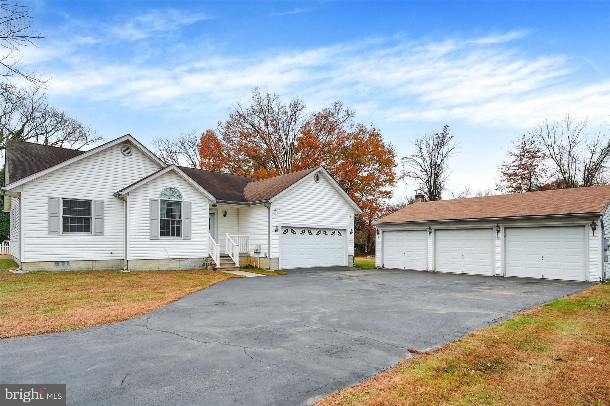 a view of a white house with a big yard and large trees