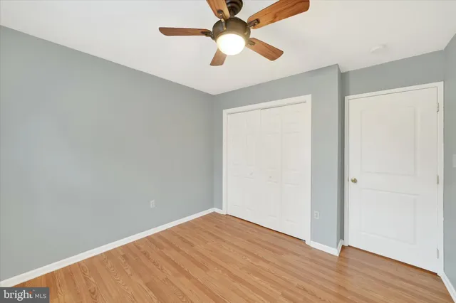an empty room with wooden floor a ceiling fan and closet