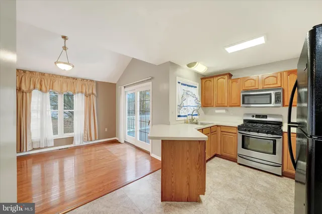 a kitchen with stainless steel appliances granite countertop a stove top oven a sink dishwasher a refrigerator and white cabinets with wooden floor
