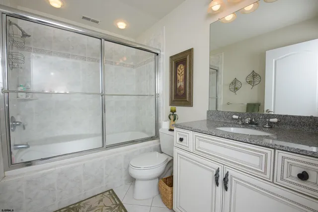 a bathroom with a granite countertop sink mirror vanity and toilet