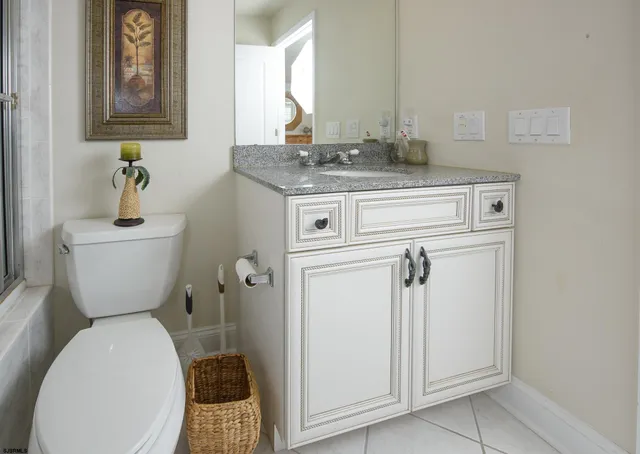 a bathroom with a granite countertop toilet sink and mirror