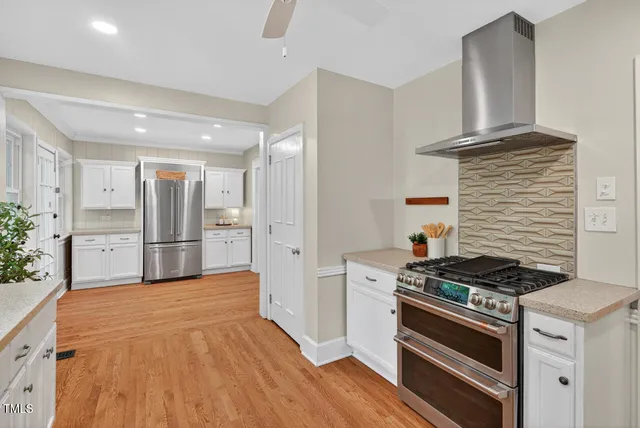 a large kitchen with stainless steel appliances a stove a sink dishwasher and a refrigerator with wooden floor