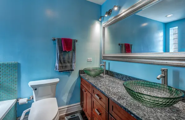 a bathroom with a granite countertop toilet sink and mirror