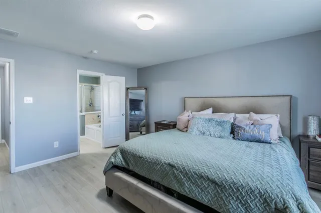 a spacious bedroom with a bed and a view of kitchen