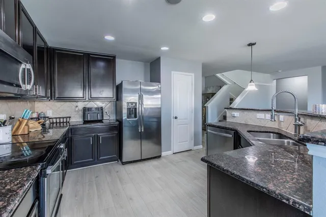 a kitchen with stainless steel appliances granite countertop a sink a stove and a wooden floors
