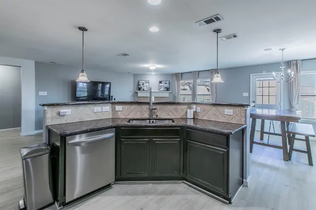a kitchen with stainless steel appliances granite countertop a sink a stove and a wooden floors
