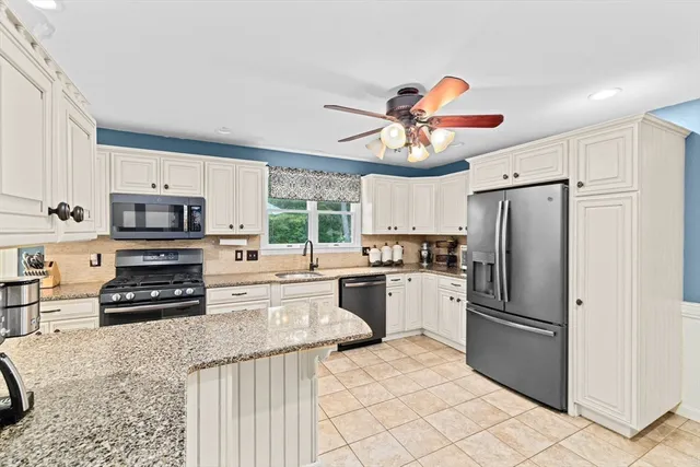 a kitchen with stainless steel appliances granite countertop a refrigerator oven a stove top oven and a sink