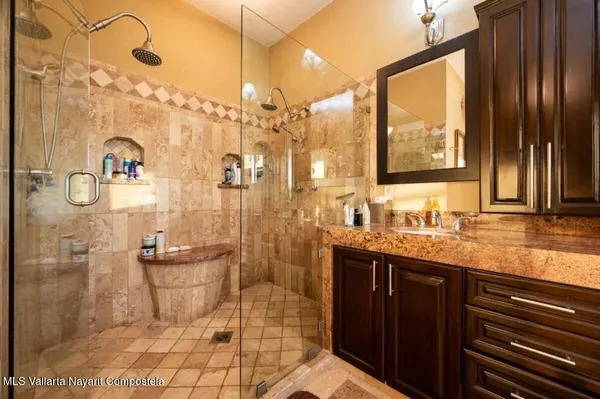 a bathroom with a granite countertop sink a toilet a mirror and shower