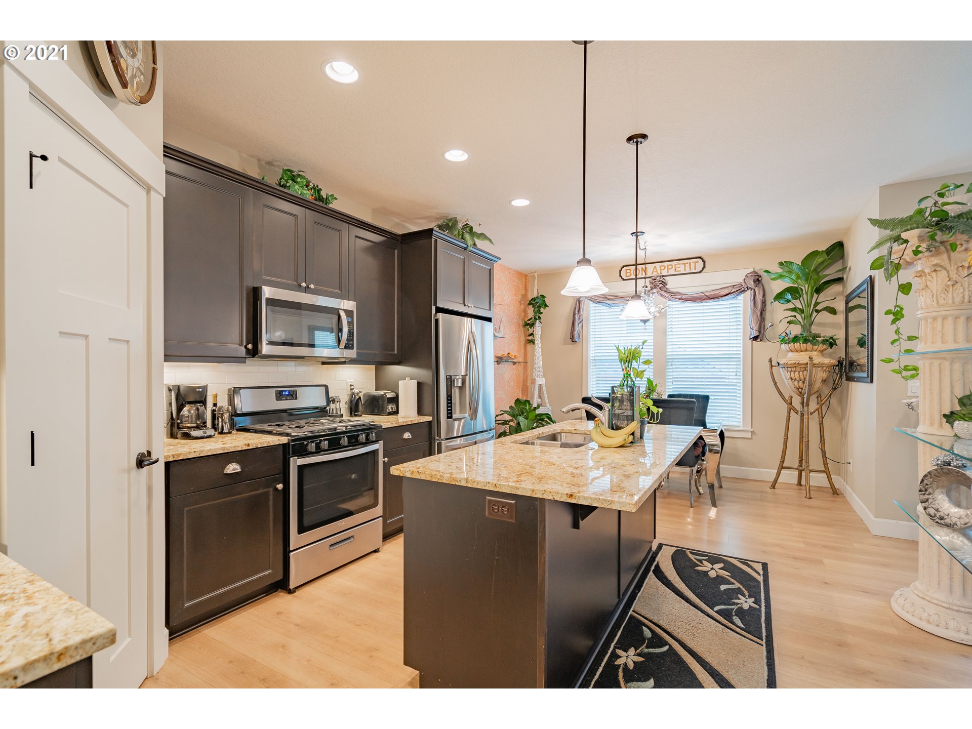 1248 South Quail Run Place Ridgefield, WA 98642 - Photo 6 of 28 a kitchen with stainless steel appliances kitchen island granite countertop a sink a stove a oven a dining table and chairs with wooden floor