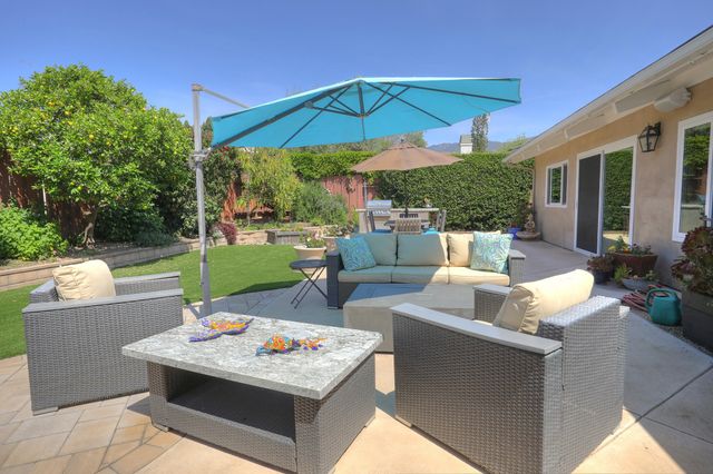a view of a patio with couches table and chairs under an umbrella