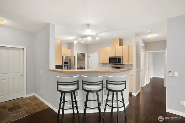 a kitchen with stainless steel appliances kitchen island granite countertop a dining table chairs and a refrigerator