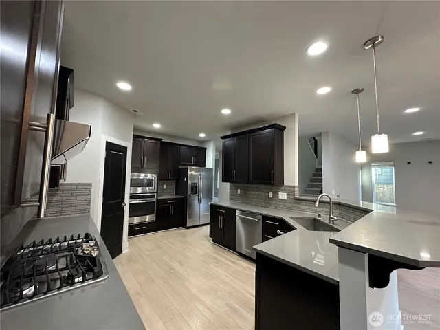 a large kitchen with a large counter top stainless steel appliances and cabinets