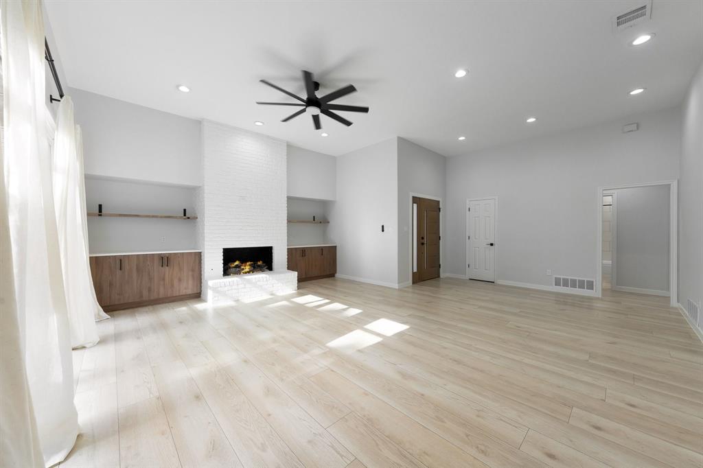 14140 Regency Place Dallas, TX 75254 - Photo 6 of 38 Spacious interior featuring light wood-finish flooring and a white brick fireplace with built-in cabinetry and shelving