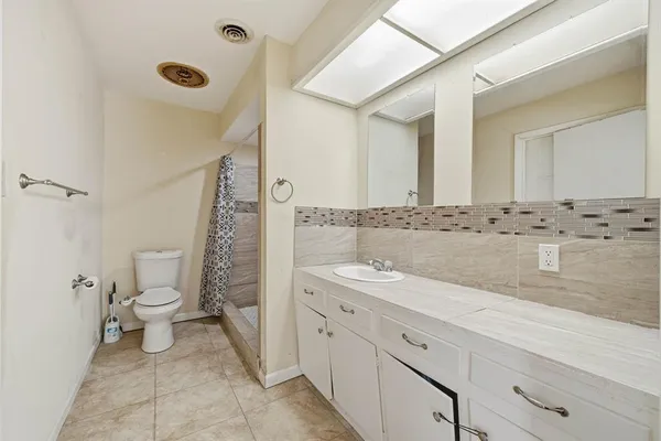 a spacious bathroom with a granite countertop sink and a toilet