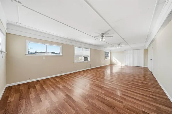a view of empty room with wooden floor and fan