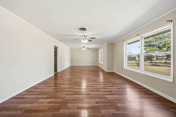 a view of empty room with wooden floor and fan