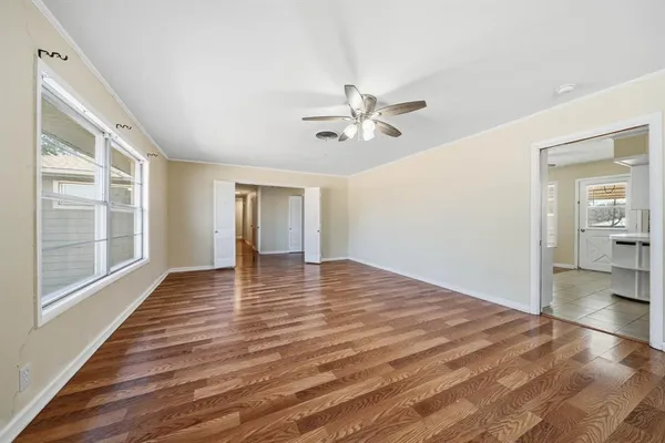 a view of empty room with wooden floor and fan