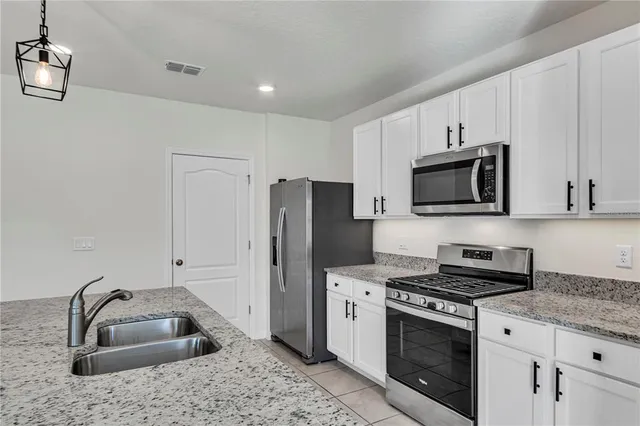 a kitchen with granite countertop a sink stainless steel appliances and white cabinets