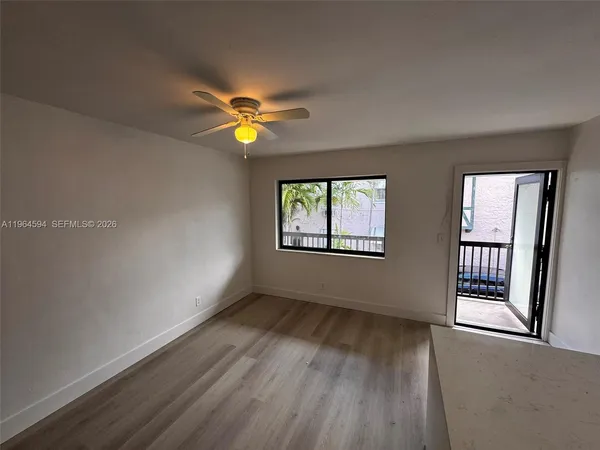 an empty room with windows and chandelier fan