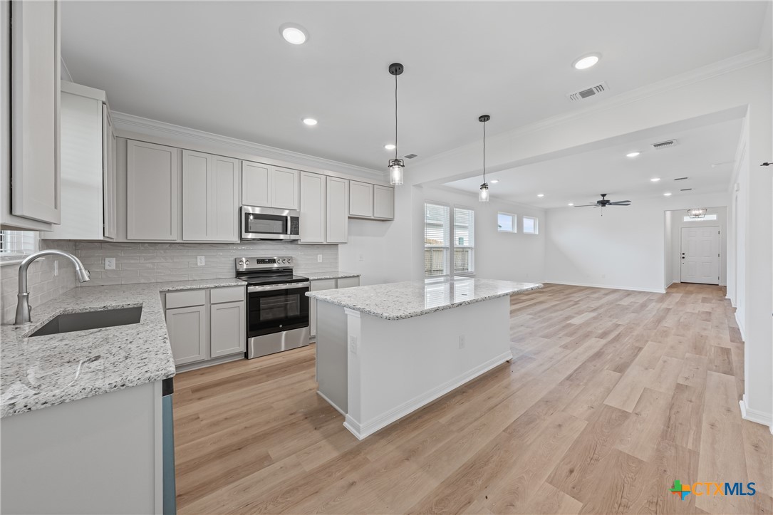 8019 Pineridge Way Temple, TX 76502 - Photo 17 of 32 a large kitchen with granite countertop a stove top oven a sink a counter space and cabinets