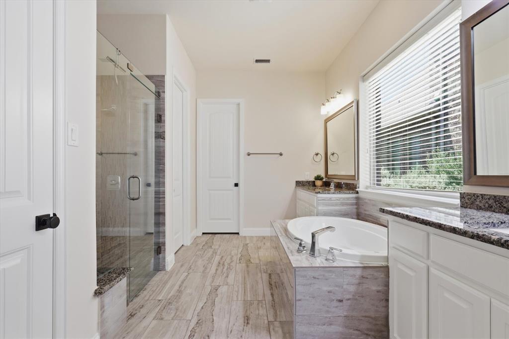 2433 Mare Road Carrollton, TX 75010 - Photo 16 of 37 Walk-in shower with glass enclosure, soaking tub, dual vanities with stone countertops, and wood-finish flooring. Large Walk In Closet.