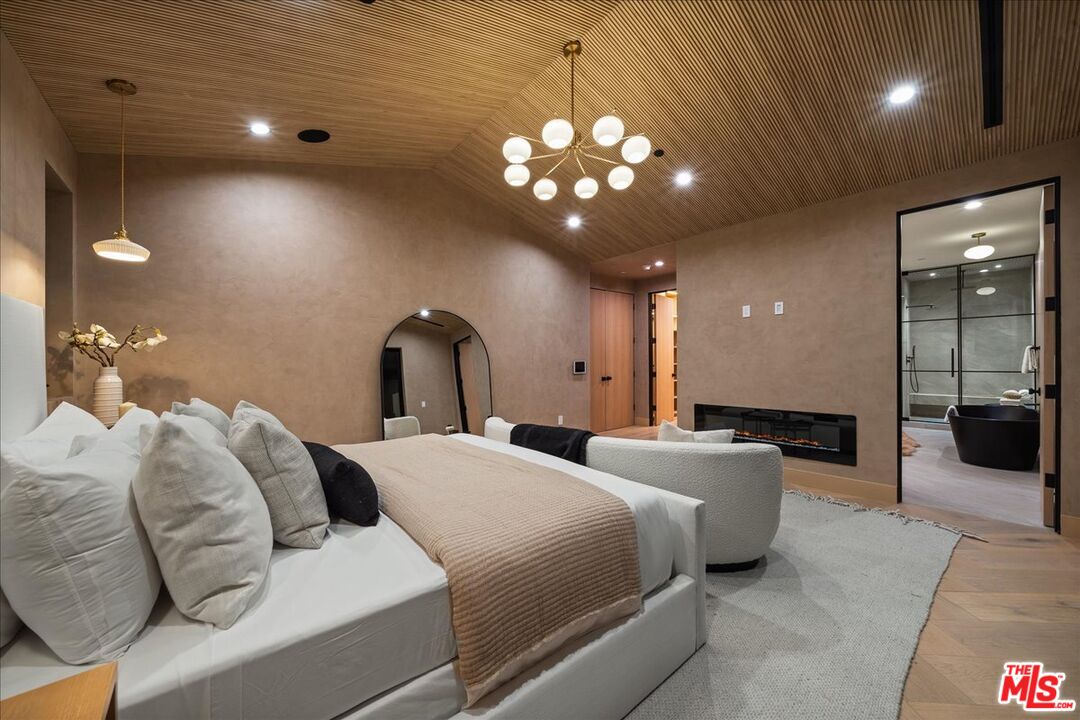 11317 Valley Spring Lane Studio City, CA 91602 - Photo 20 of 40 a large bedroom with a large bed and a chandelier