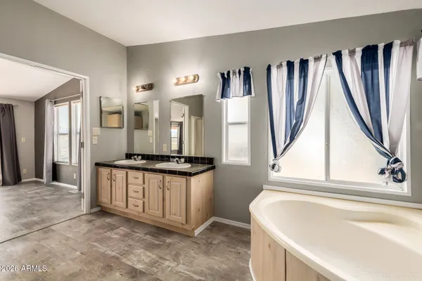 a bathroom with a granite countertop double vanity sink a mirror and a bathtub
