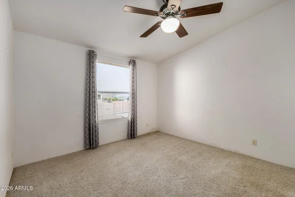 an empty room with closet and a ceiling fan