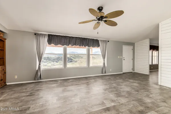 a view of a livingroom with a fireplace a ceiling fan and windows