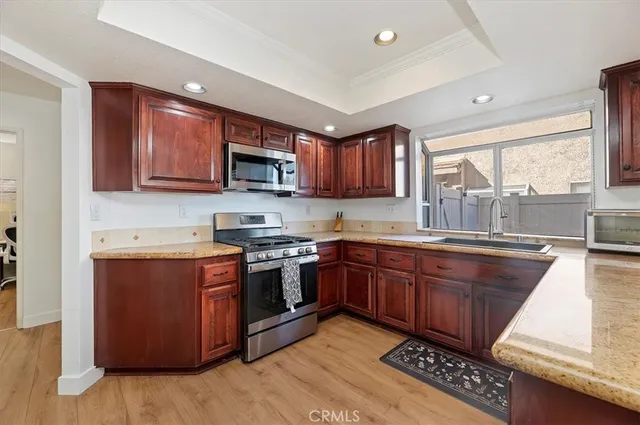 a kitchen with stainless steel appliances granite countertop wooden cabinets a stove a sink and a window