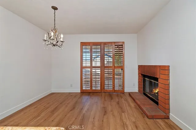 an empty room with wooden floor fireplace and windows