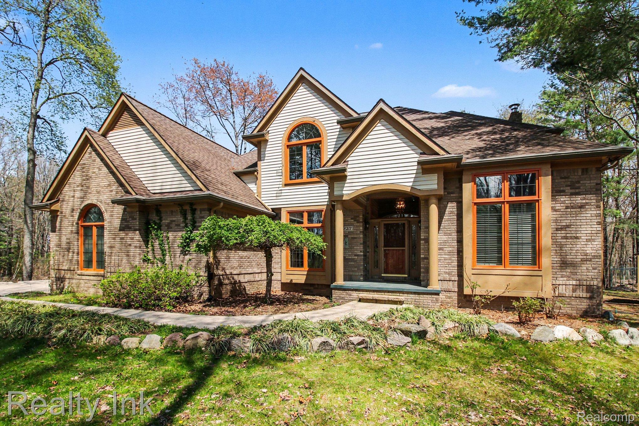 View of front of property with brick siding, a front lawn, and a chimney